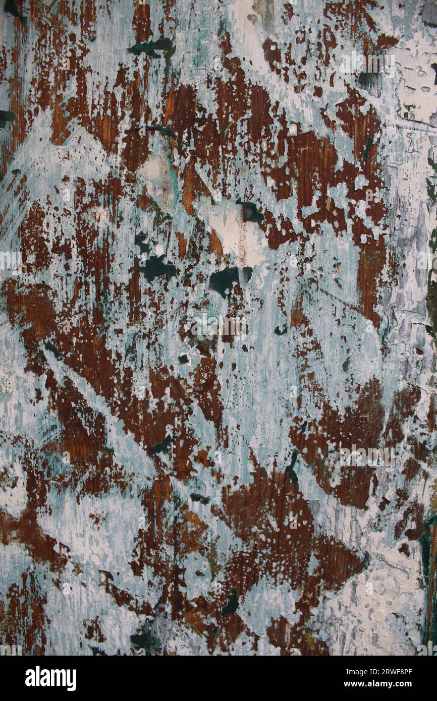 A Wooden Door seen close up and abstract. The paint work is chipped & worn revealing different layers and colours giving a vintage distressed look. Stock Photo