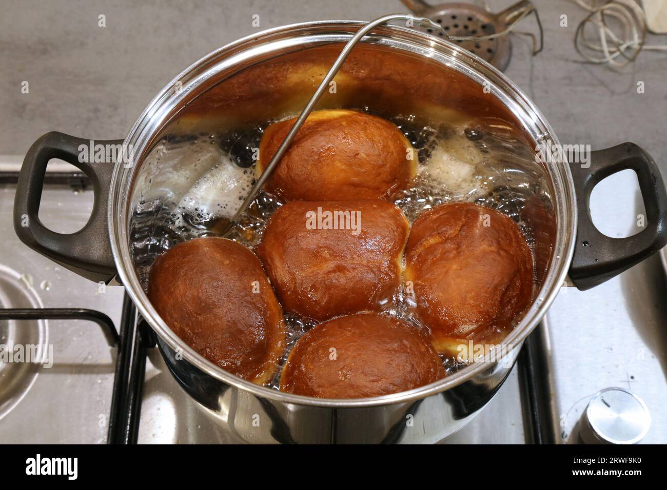Making homemade yeast raised donuts - deep frying in lard fat with a kitchen thermometer probe. Polish donuts made for Tlusty Czwartek (Fat Thursday) Stock Photo