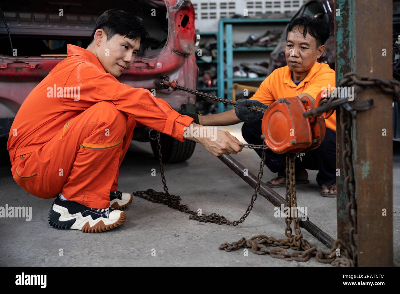 Mechanic testing strength and reliability of chain hoist for car towing