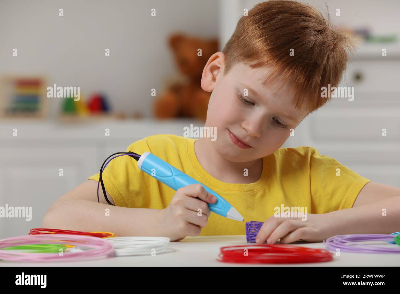 Boy drawing with stylish 3D pen at white table Stock Photo