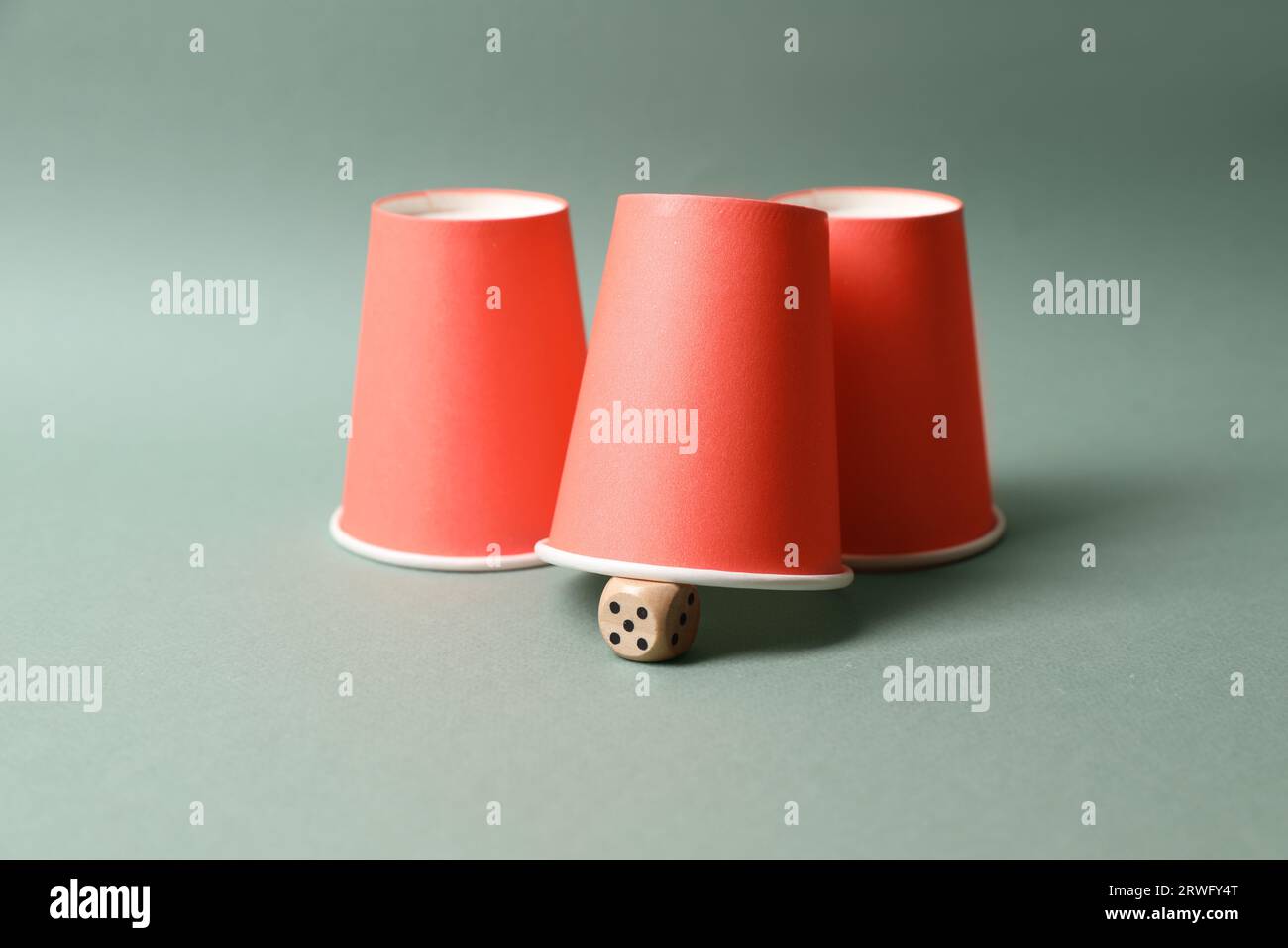 Three red cups and dice on pale olive background. Thimblerig game Stock ...