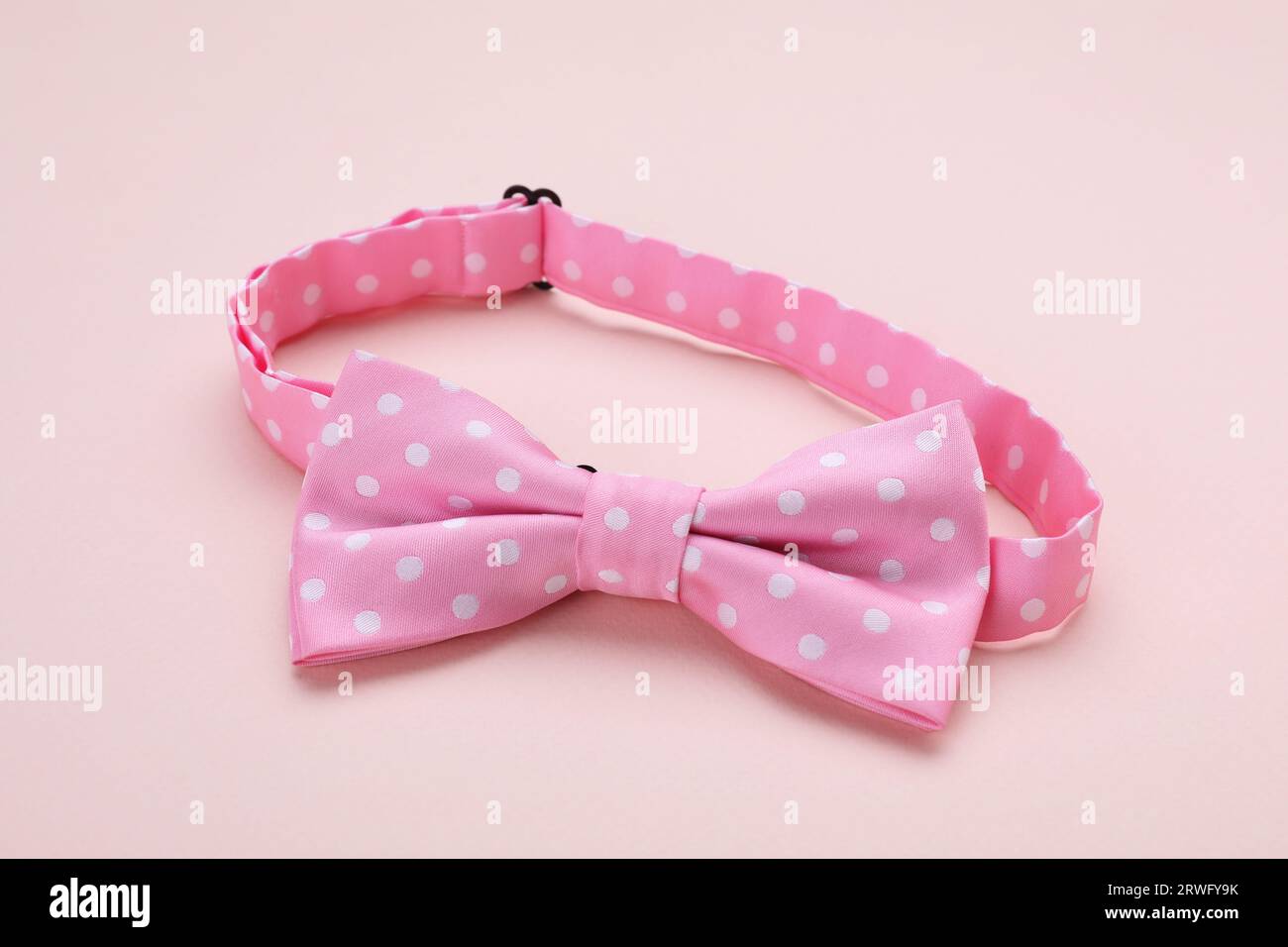 Stylish pink bow tie with polka dot pattern on beige background Stock Photo