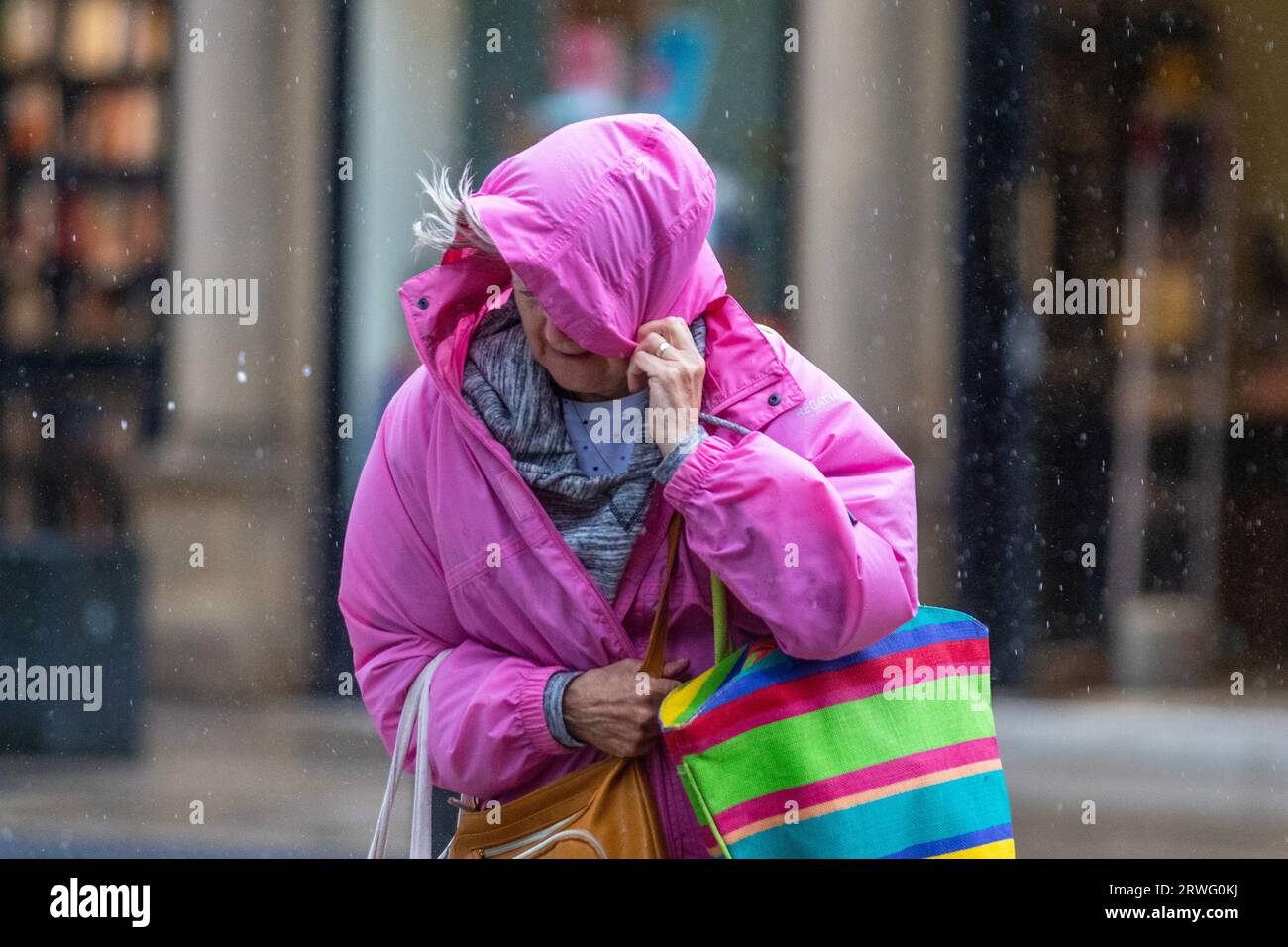 Woman holding hood over face on a rainy day Preston, Lancashire.  UK Weather 19 Sept 2023. Shops, shoppers shopping on a gusty windy day with heavy showers in Preston. Remaining windy, with gales locally in the west. Spells of heavy and persistent rain are expected this afternoon. Stock Photo
