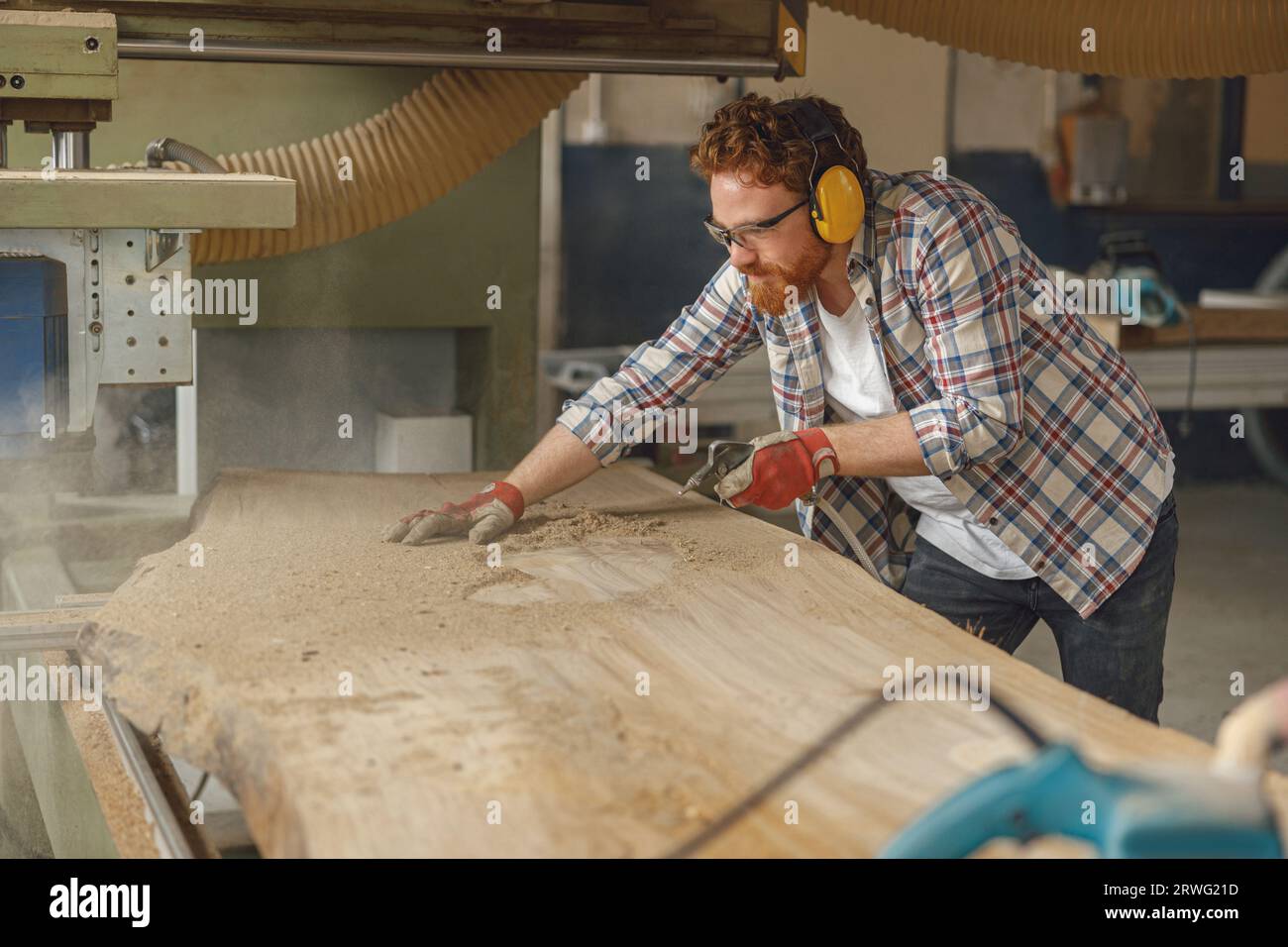 Carpenter is cleaning saw from sawdust with air compressor working in