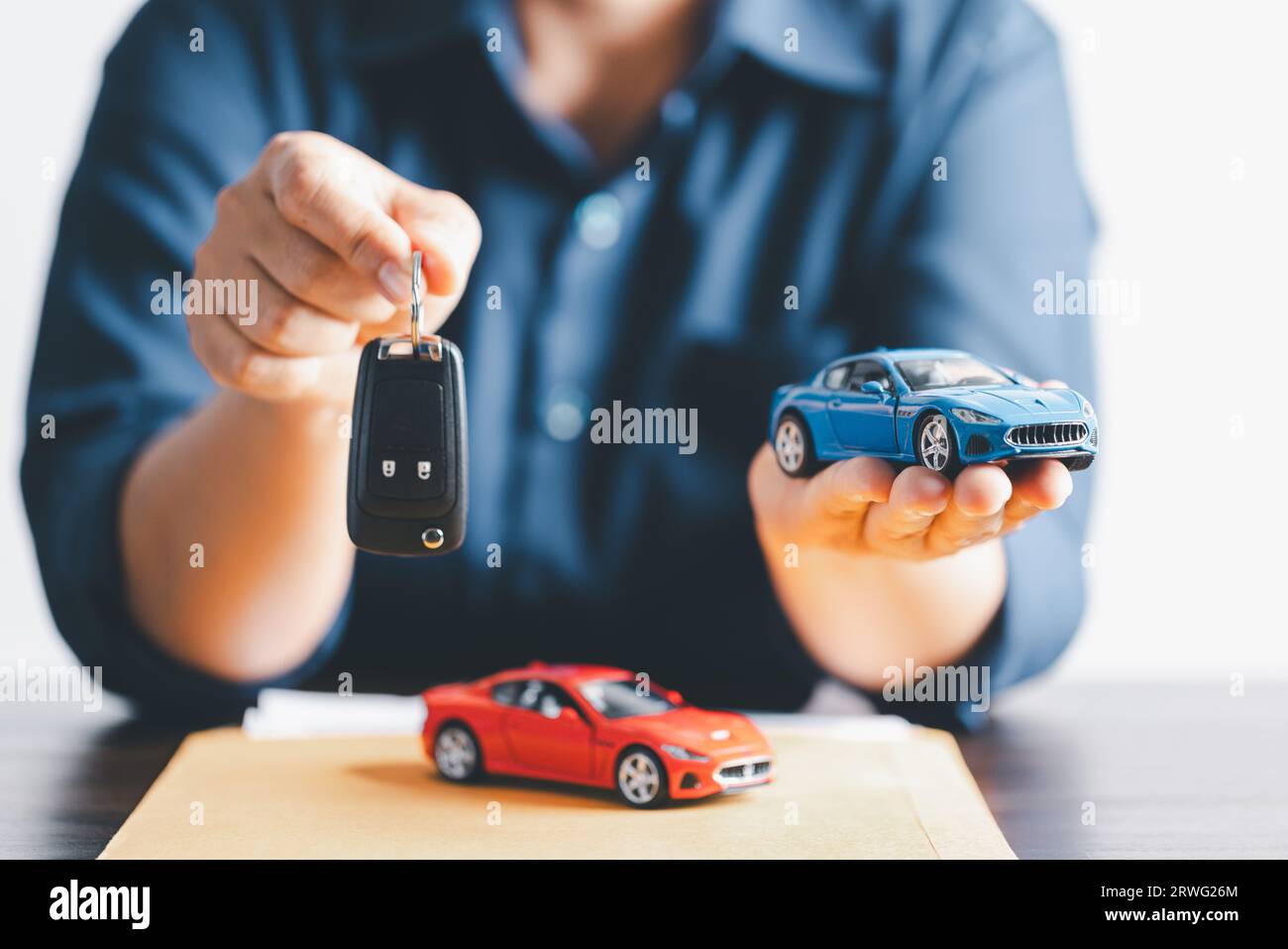 Hand holding car keys and a remote control for keyless entry. Car loan