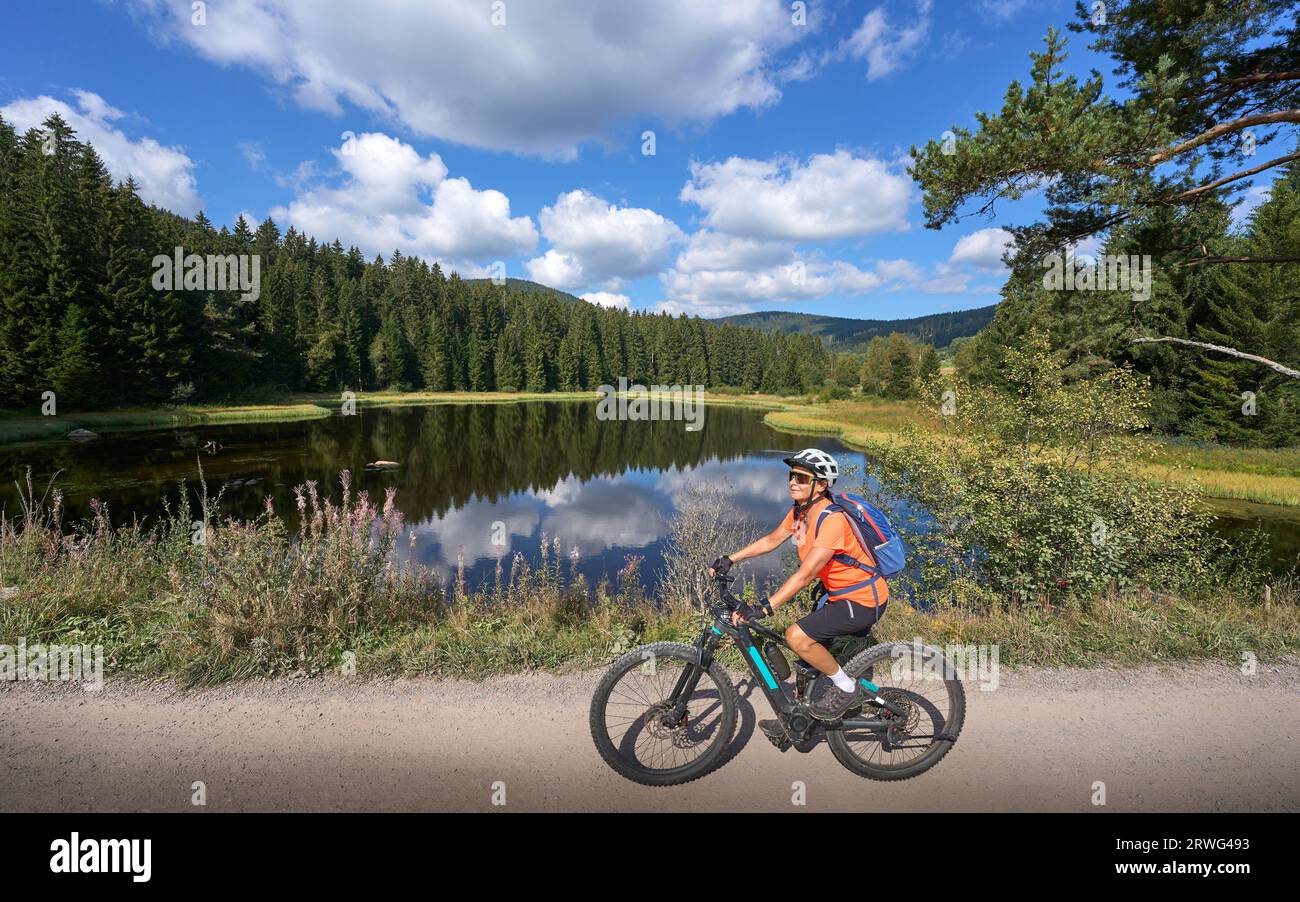 nice senior woman on her electric mountain bike cycling at Lake Schluchsee in the German Black Forest near Titisee-Neustadt, Baden-Württemberg, German Stock Photo
