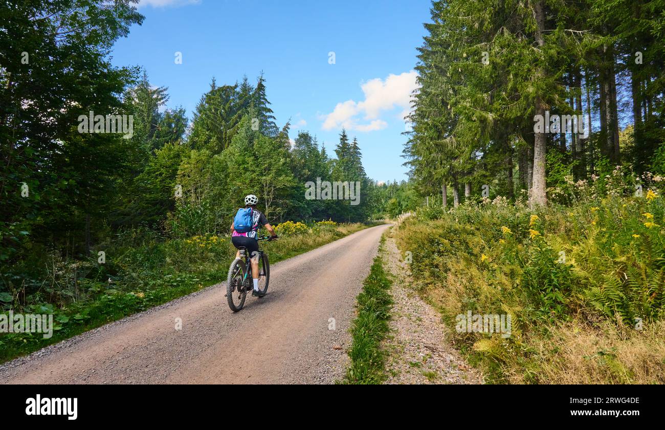 nice senior woman on her electric mountain bike cycling in the German Black Forest near Titisee-Neustadt, Baden-Württemberg, Germany Stock Photo