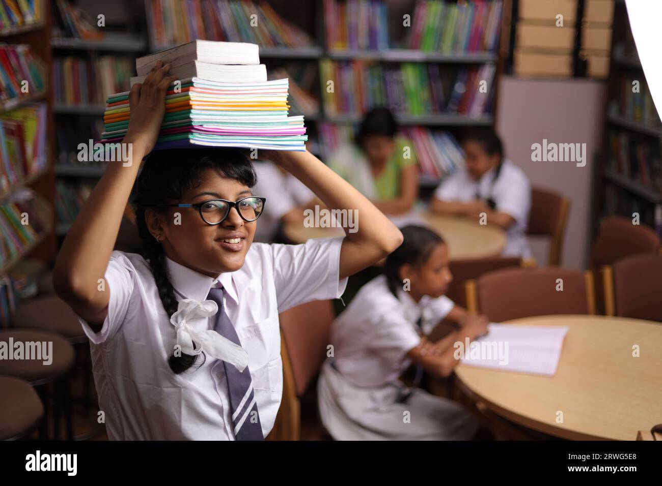 Happy teenager girl student holding books on her head, standing in ...