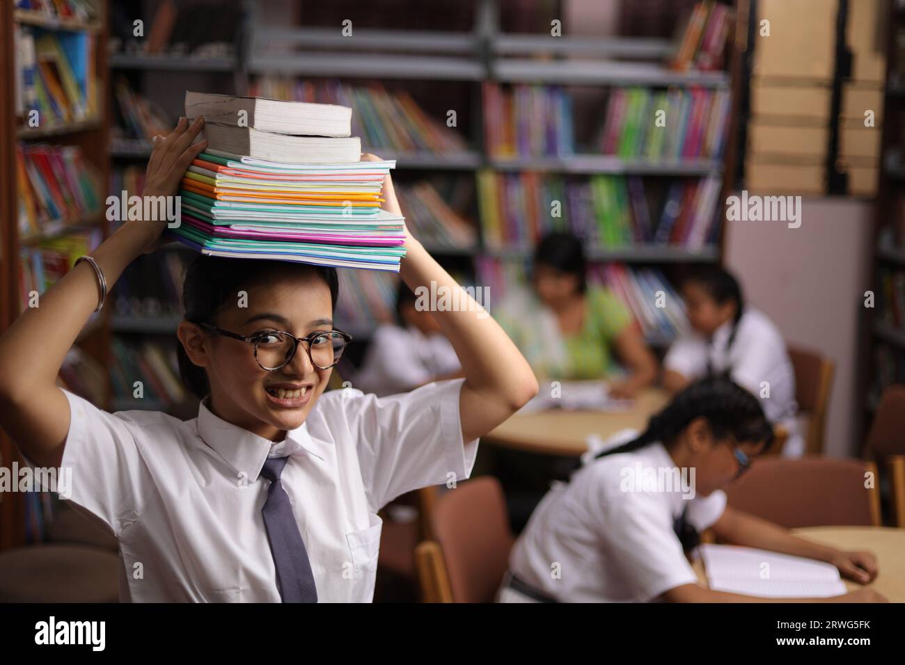 Happy teenager girl student holding books on her head, standing in ...