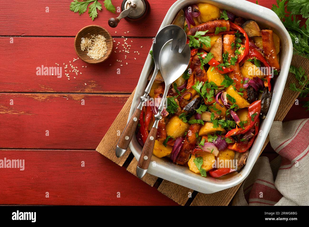 Baked sausage and vegetables, peppers, zucchini, tomatoes, red onion and eggplant with sesame and cilantro served hot from oven on baking tray. Tradit Stock Photo