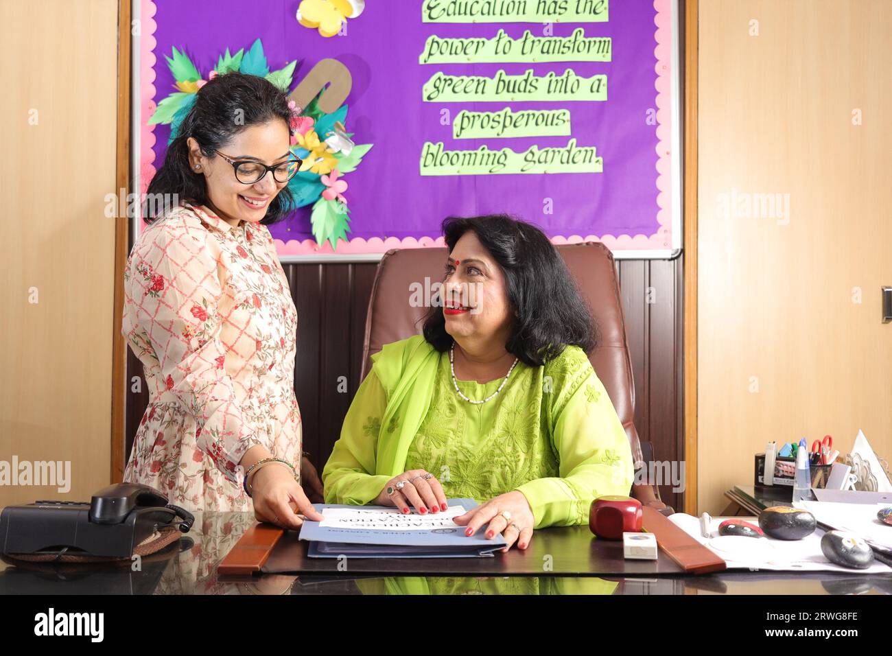 School Principal mam checking some important documents in a file with her personal assistant, discussion, signing the documents, progress in education Stock Photo