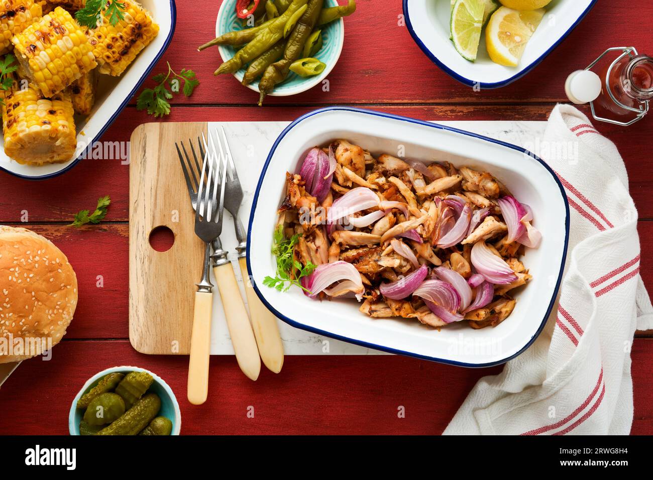 Pulled bbq chicken with baked onions on serving platter, bbq corn