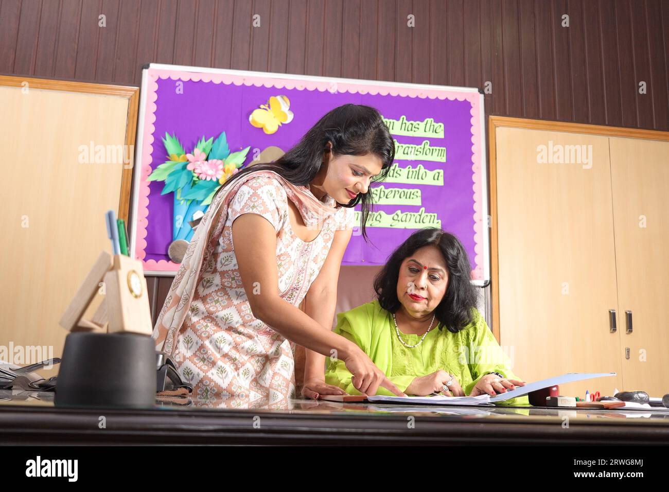 School Principal mam checking some important documents in a file with her personal assistant, discussion, signing the documents, progress in education Stock Photo