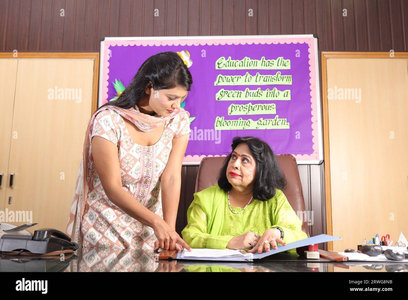 School Principal mam checking some important documents in a file with her personal assistant, discussion, signing the documents, progress in education Stock Photo