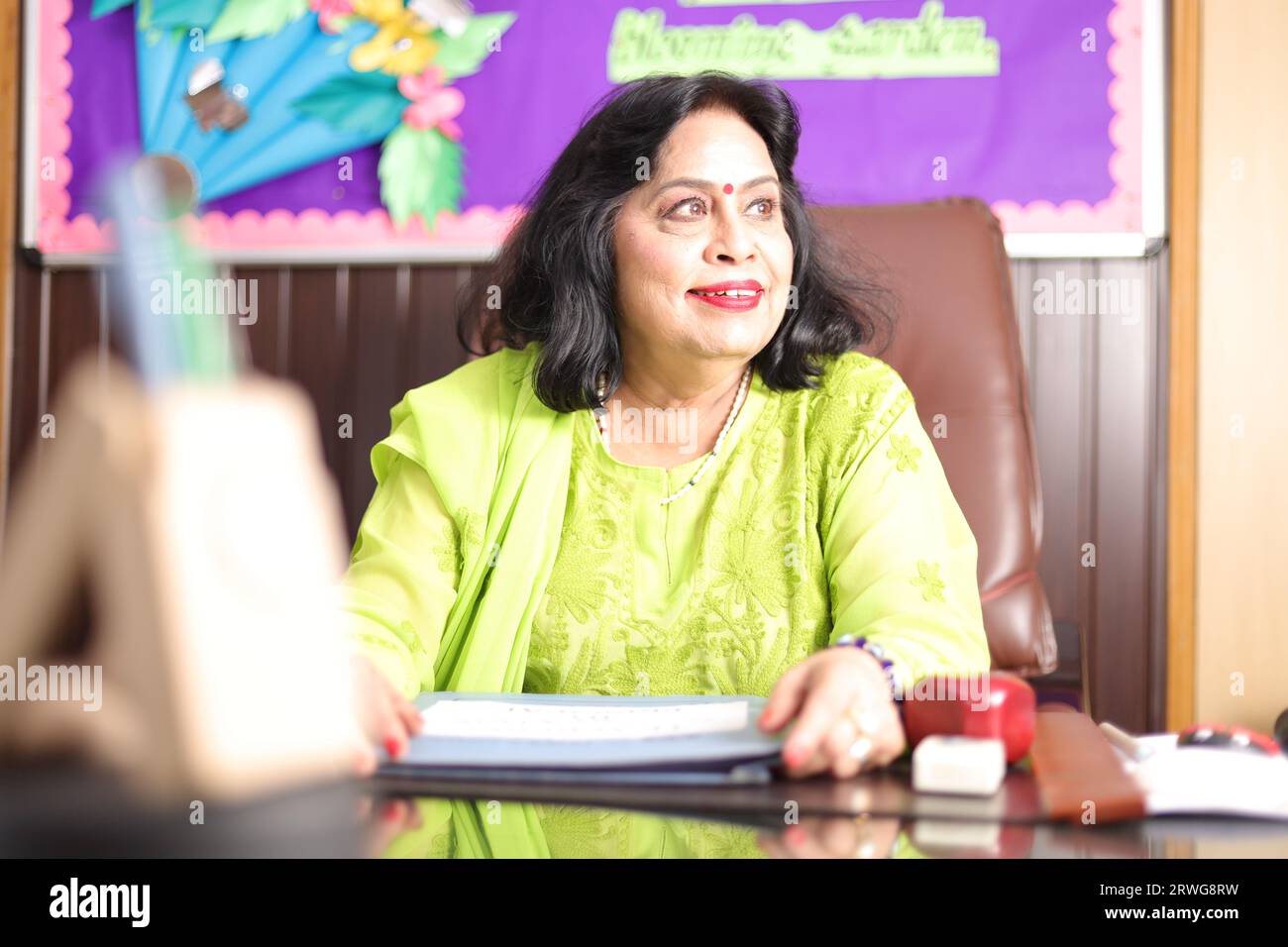 School Principal mam sitting happily, proud of the students of her school, smiling. Stock Photo