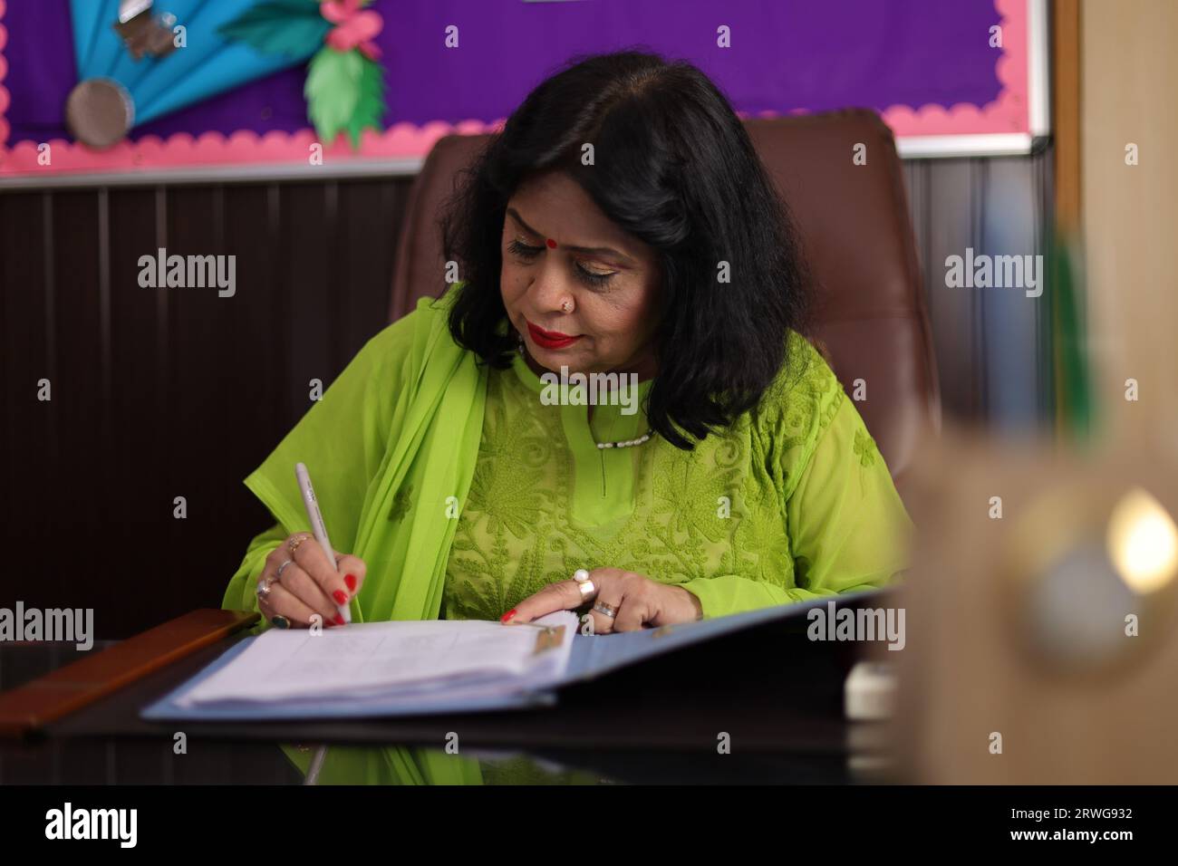 Principal mam signing a contract, agreement for the progress of the students in her school, educational progress. Stock Photo