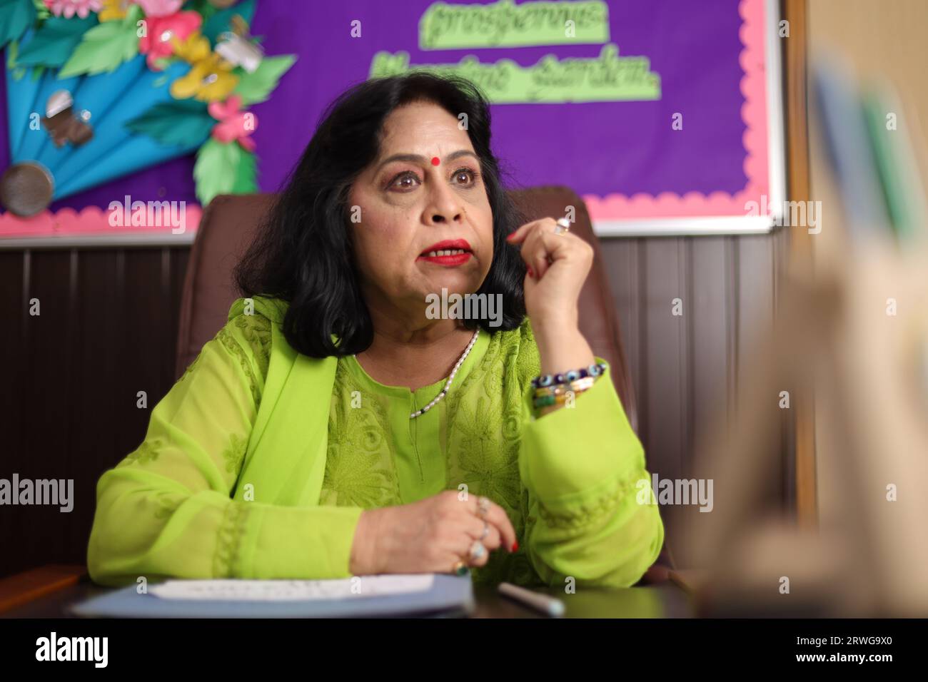 Principal of school sitting in her office with aggression, fuming with anger, furious expression. Stock Photo
