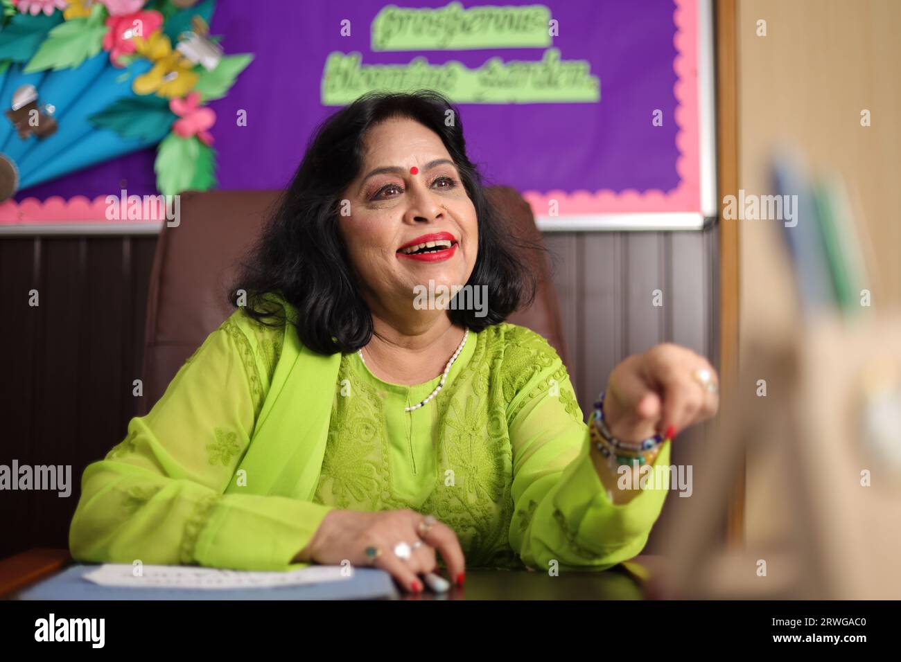 School Principal mam sitting happily, proud of the students of her school, smiling. Stock Photo