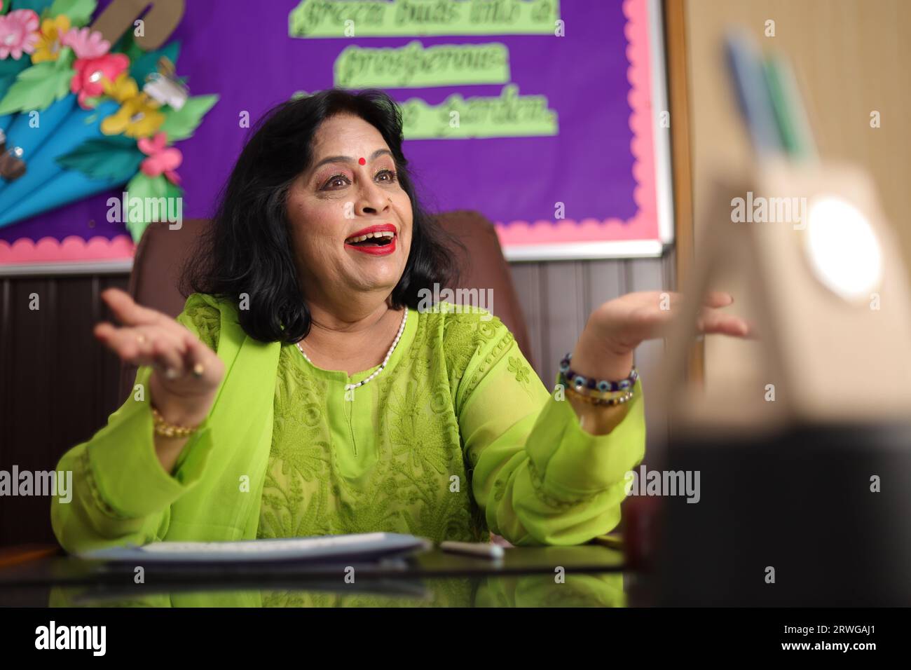 School Principal mam sitting happily, proud of the students of her school, smiling. Stock Photo