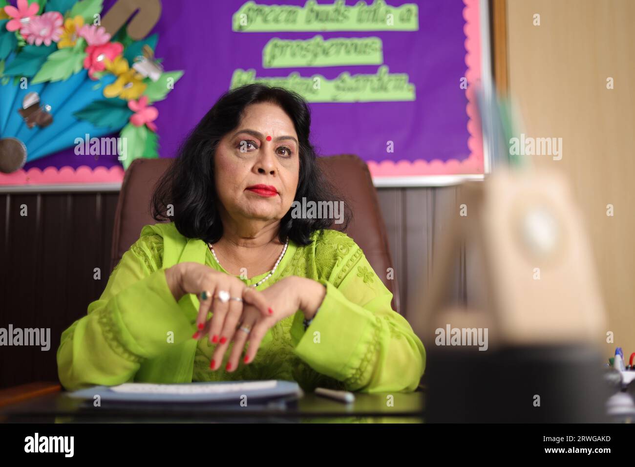 School Principal mam sitting happily, proud of the students of her school, smiling. Stock Photo