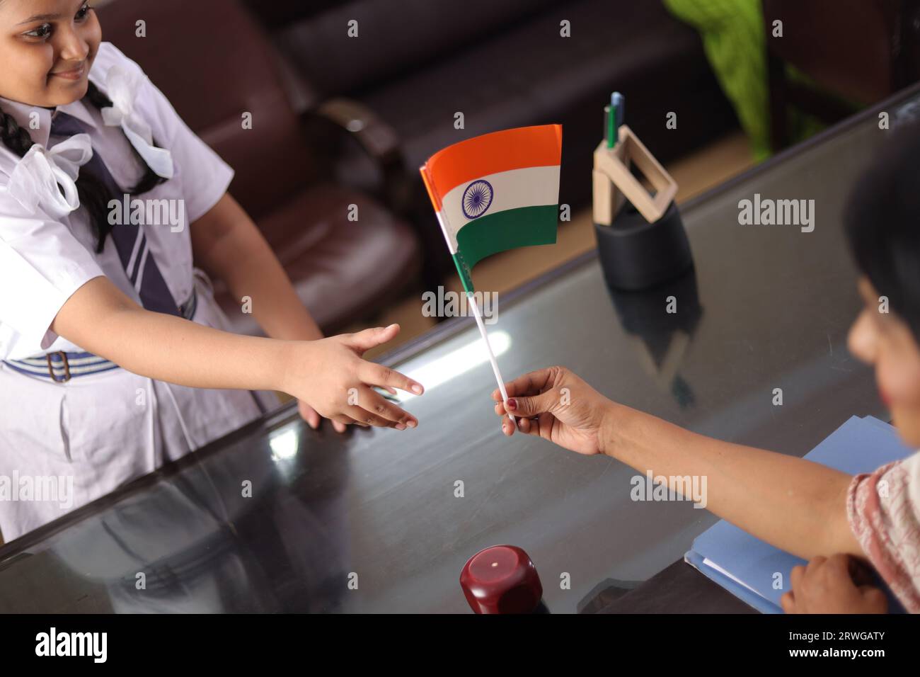 Happy proud Principal, teacher personally giving, offering Indian flag as a gift, award to a student  for her promotion in school. Stock Photo