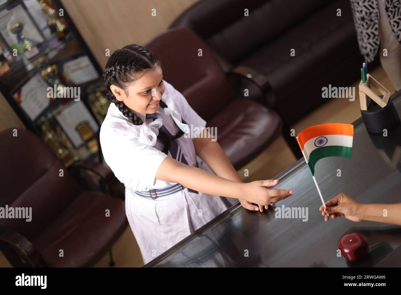 Happy proud Principal, teacher personally giving, offering Indian flag as a gift, award to a student  for her promotion in school. Stock Photo