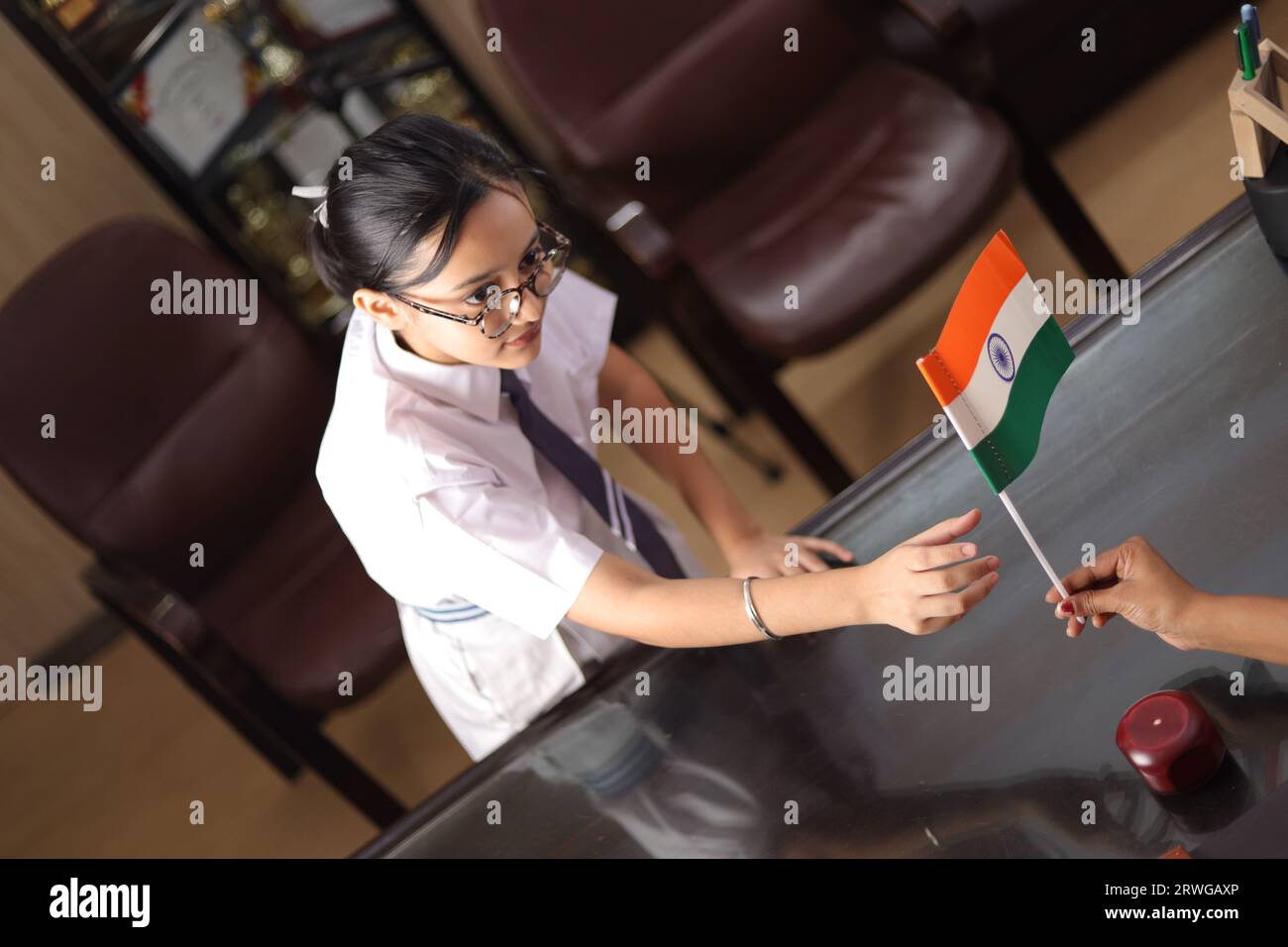Happy proud Principal, teacher personally giving, offering Indian flag as a gift, award to a student  for her promotion in school. Stock Photo