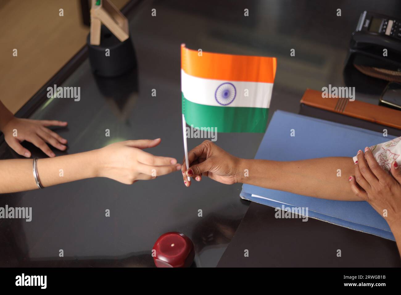 Happy proud Principal, teacher personally giving, offering Indian flag as a gift, award to a student  for her promotion in school. Stock Photo