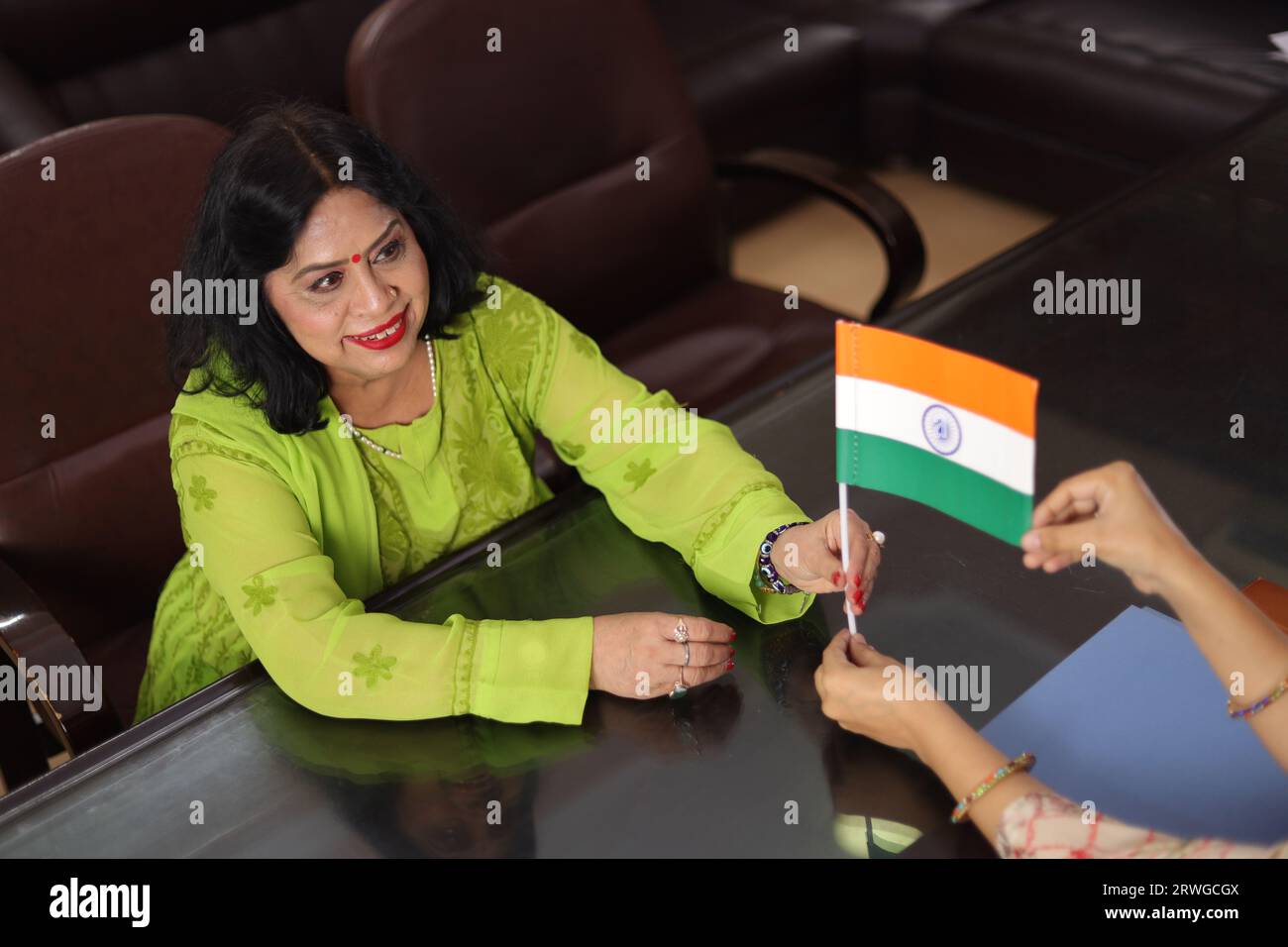 Principal Ma'am giving an Indian flag to a teacher as a gift, parent teacher meeting, PTM, women, principal office, courtesy, professionalism, award. Stock Photo