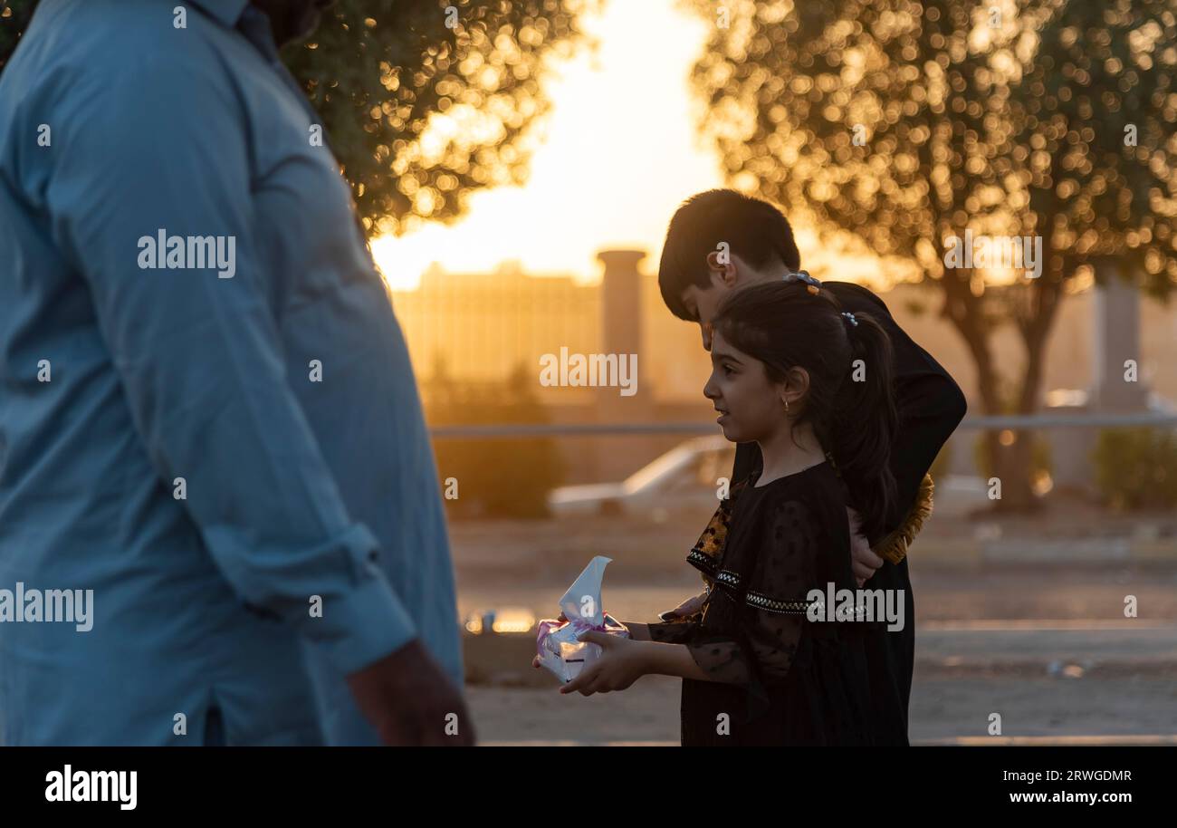 An Iraqi Shia girl distribute tissue papers among Shia Muslim pilgrims marching from Najaf towards Shrine city of Karbala. Every year, millions of Shia Muslims and some from other faiths undertake a 20-day pilgrimage on foot from various cities in Iraq and Iran to the holy city of Karbala. This pilgrimage is in remembrance of Imam Hussein, the grandson of the Prophet Muhammad, who died in a battle in 680 AD. On the 40th day of mourning for Hussein, known as Arbaeen, pilgrims converge in Karbala to pay tribute at his shrine. Along the way, volunteers provide food, water, and shelter, and villag Stock Photo