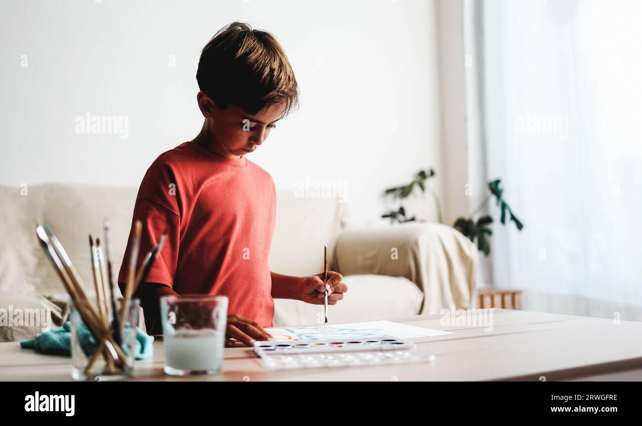 Latin kid painting with watercolors on canvas at home - School homework education concept Stock Photo