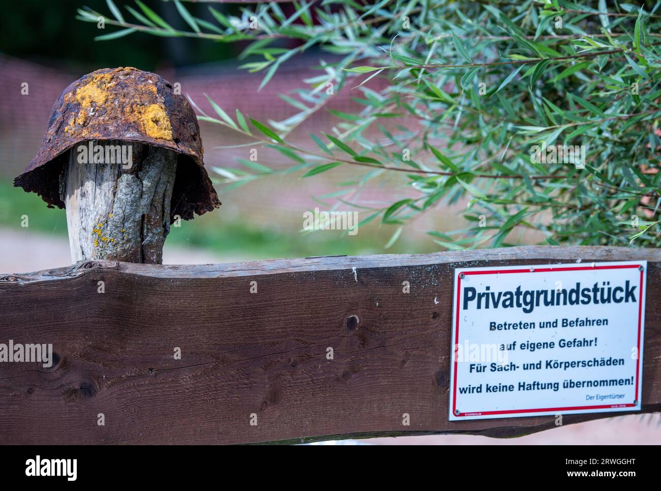 Jamel, Germany. 19th Sep, 2023. A rusty steel helmet hangs on the garden fence in front of the house of Krüger, a right-wing extremist known throughout Germany, next to a sign indicating 'private property'. Federal Interior Minister Faeser has banned the right-wing extremist association 'Hammerskins Germany' as well as its regional offshoots and the sub-organization 'Crew 38'. According to the ministry, police task forces searched the homes of 28 suspected members of the association in ten German states in the early morning. Credit: Jens Büttner/dpa/Alamy Live News Stock Photo