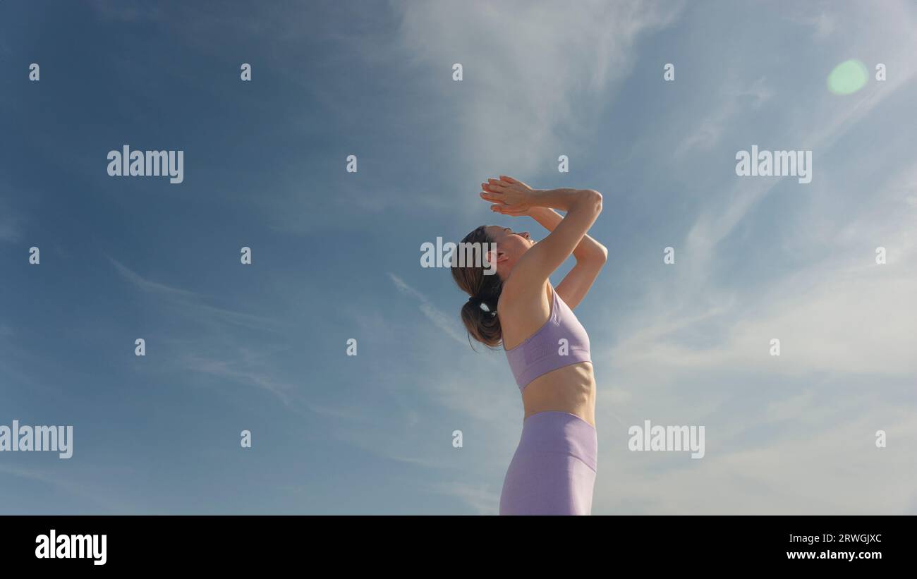 caucasian woman practicing yoga, blue sky background Stock Photo