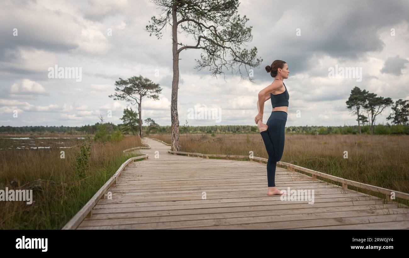 sporty woman doing and leg stretch on a boardwalk Stock Photo