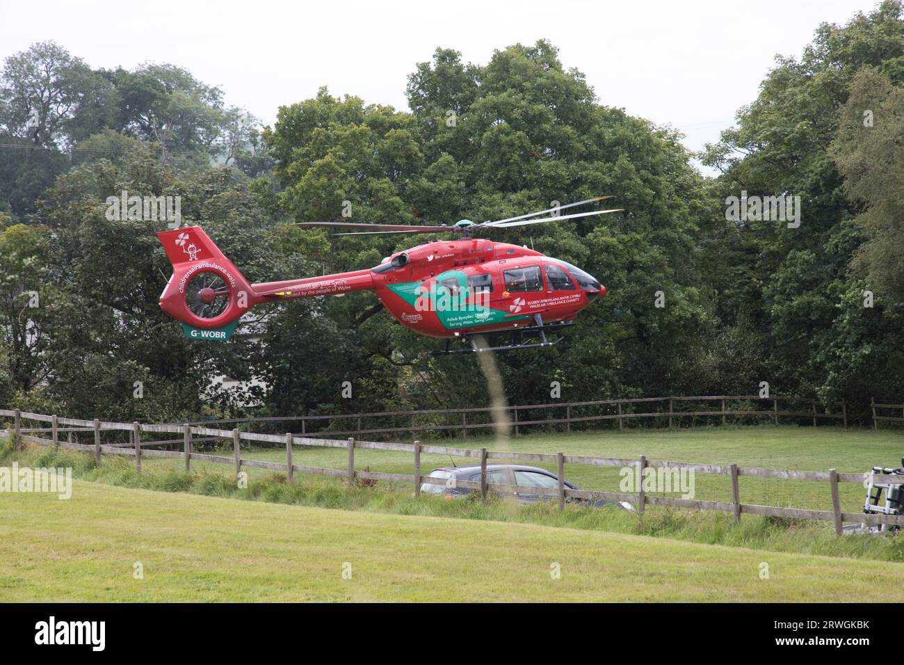 Red Wales Helicopter Ambulance landing in field at National Whitewater Centre near Bala North Wales Stock Photo