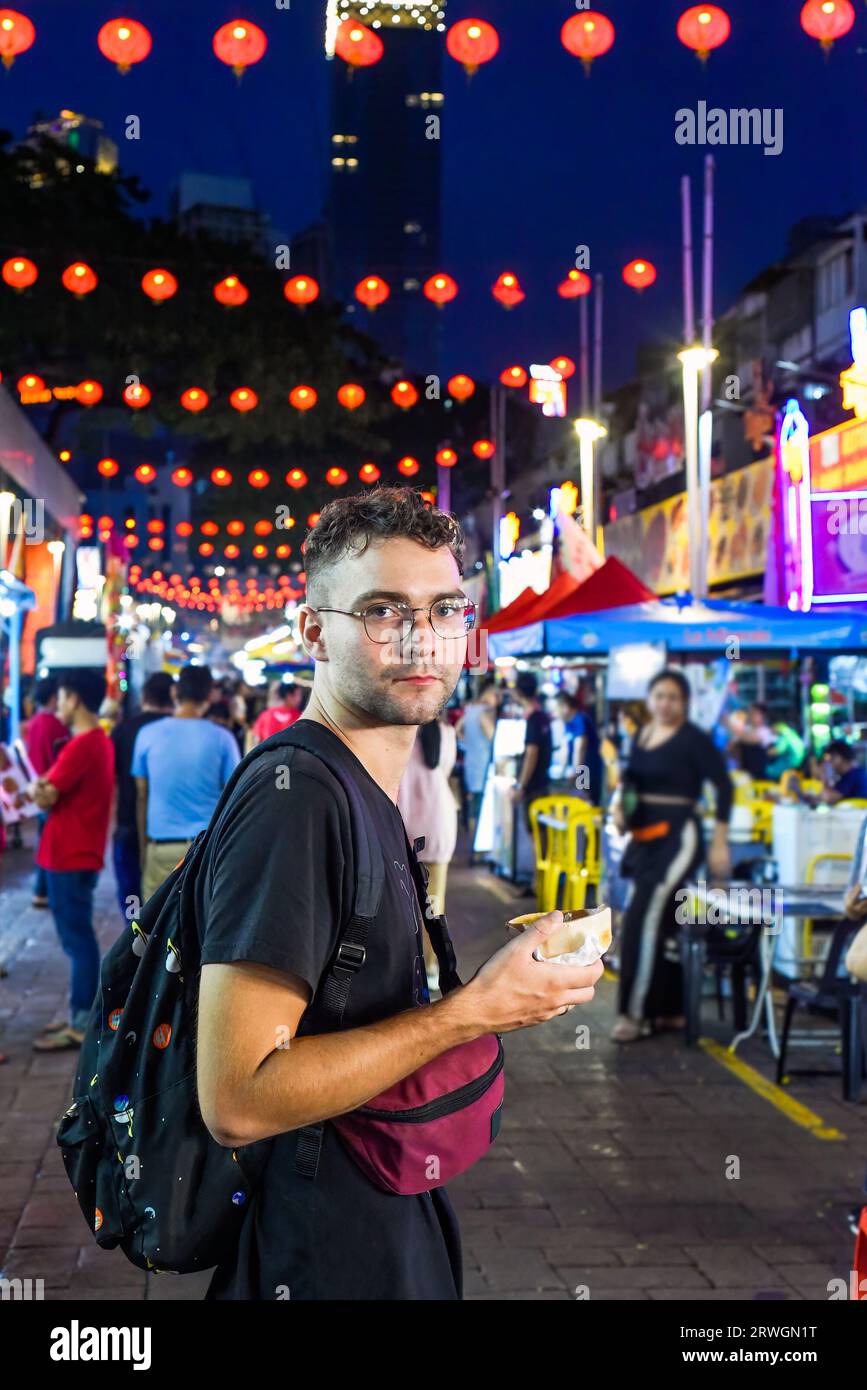 Young man tourist eating ice cream in Jalan Alor street food in Kuala Lumpur, Malaysia Stock Photo