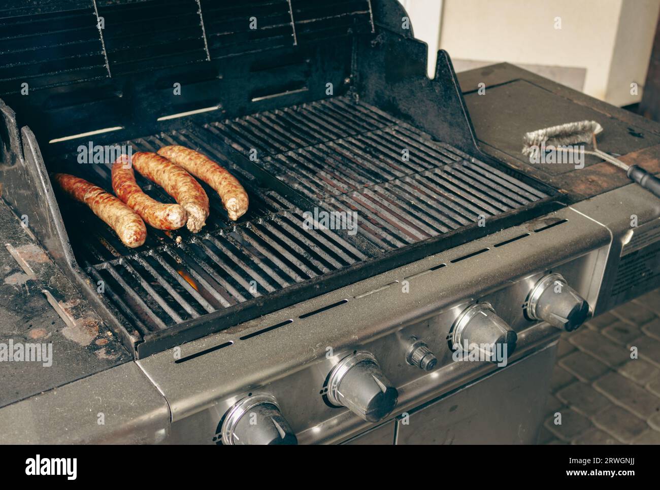 Sausages on the grill. Garden barbecue party. Pork sausages on the grill grate. Grilled bratwurst sausages. Picnic at backyard. Hot dog cooking. Stock Photo