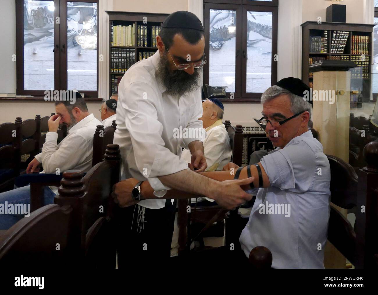 ODESA, UKRAINE - SEPTEMBER 15, 2023 - A man helps place an arm-tefillah ...