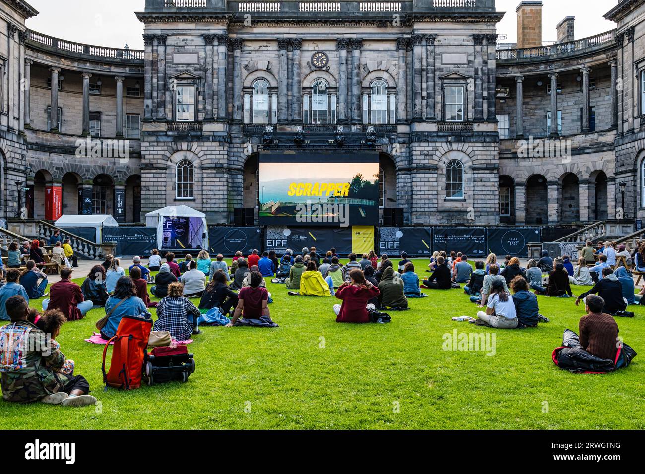 People sitting on grass to watch outdoor screening of film Scrapper, Old College Quad at Edinburgh International Film Festival, Scotland, UK Stock Photo