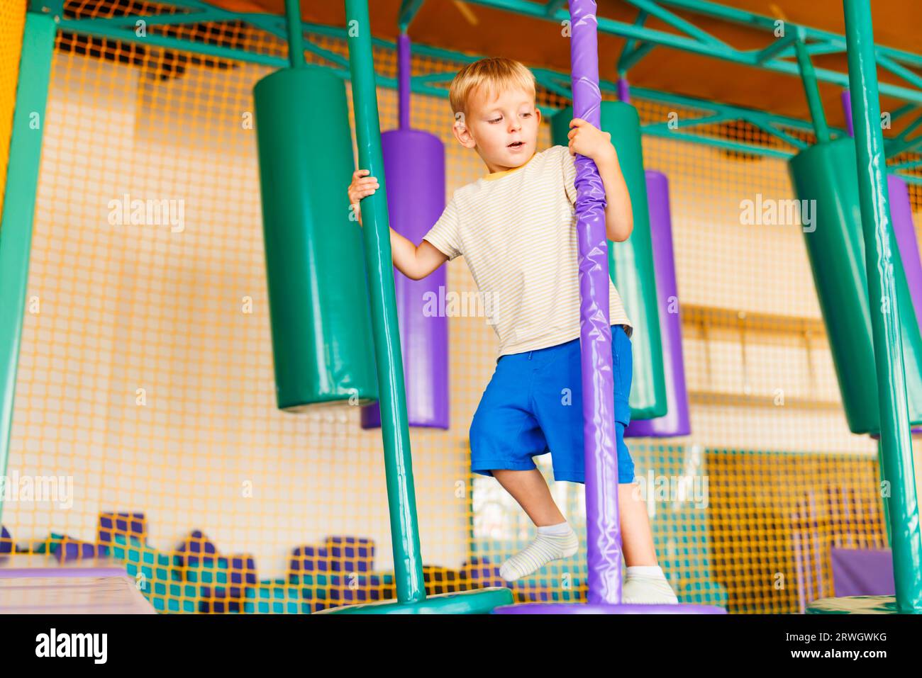 Cute little boy crawling and playing on colorful playground at amusement park Stock Photo