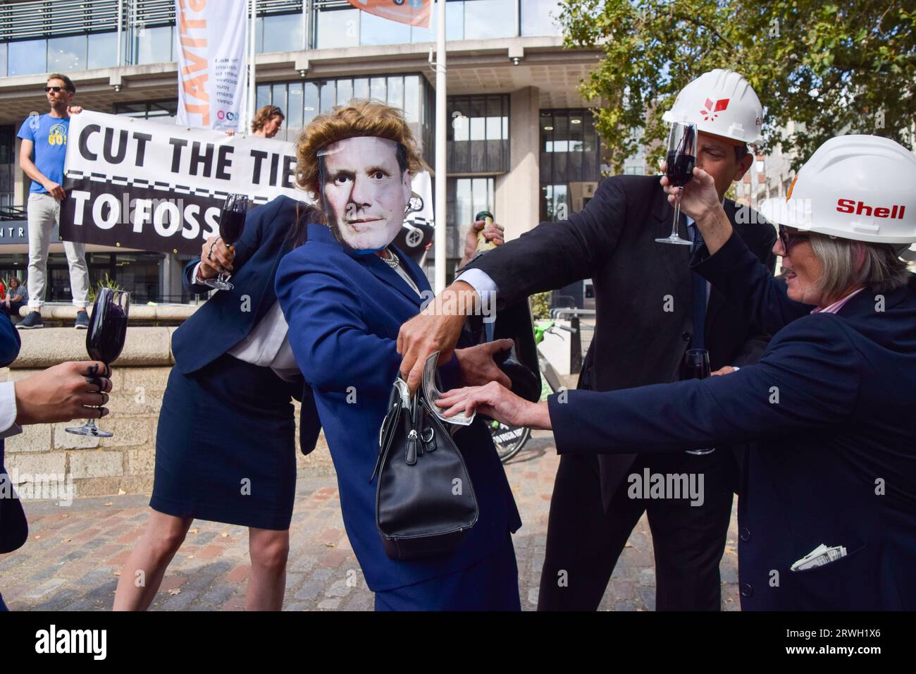 London, UK. 16th September 2023. Protesters dressed as executives from fossil fuel companies stuff fake money into the purse of a protester wearing a mask of Labour Party leader Keir Starmer as Extinction Rebellion stage a protest against new fossil fuels. Stock Photo