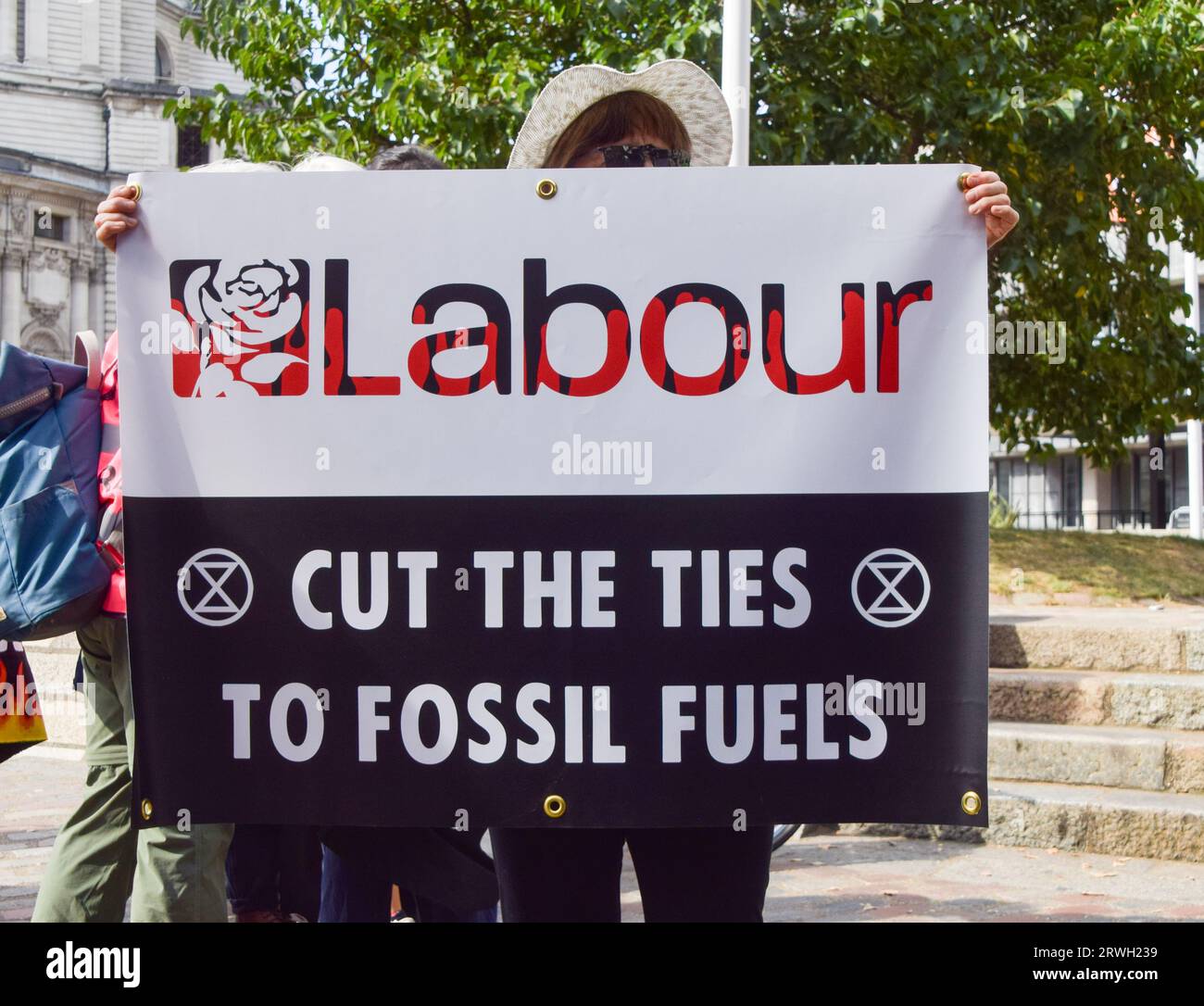London, UK. 16th September 2023. A protester in Westminster holds a banner calling on the Labour Party to cut ties to fossil fuels as Extinction Rebellion stage a protest against new fossil fuels. Stock Photo