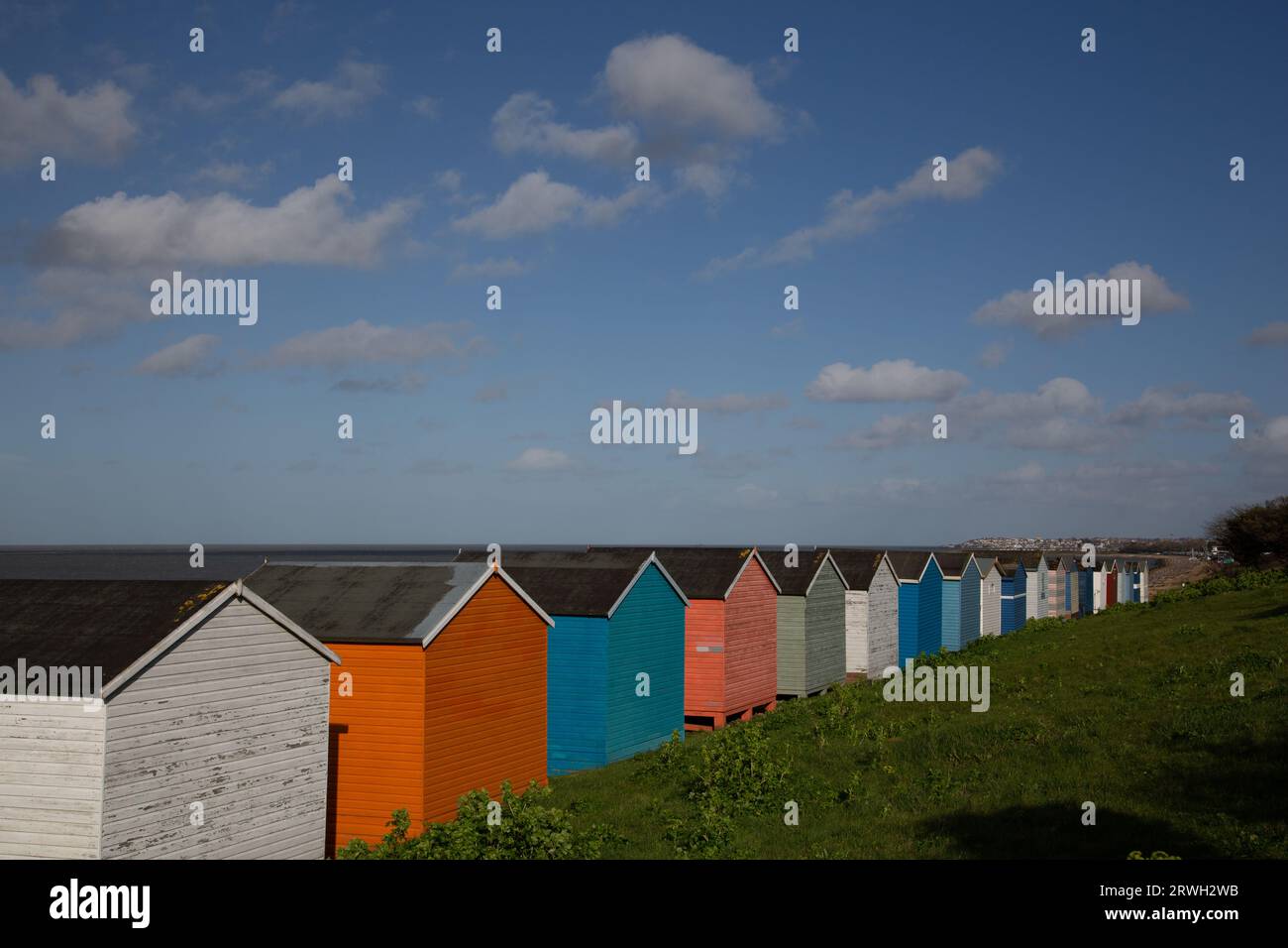 A line of colourful seaside beach huts on a summer's day with space above in the blue sky to add text Stock Photo