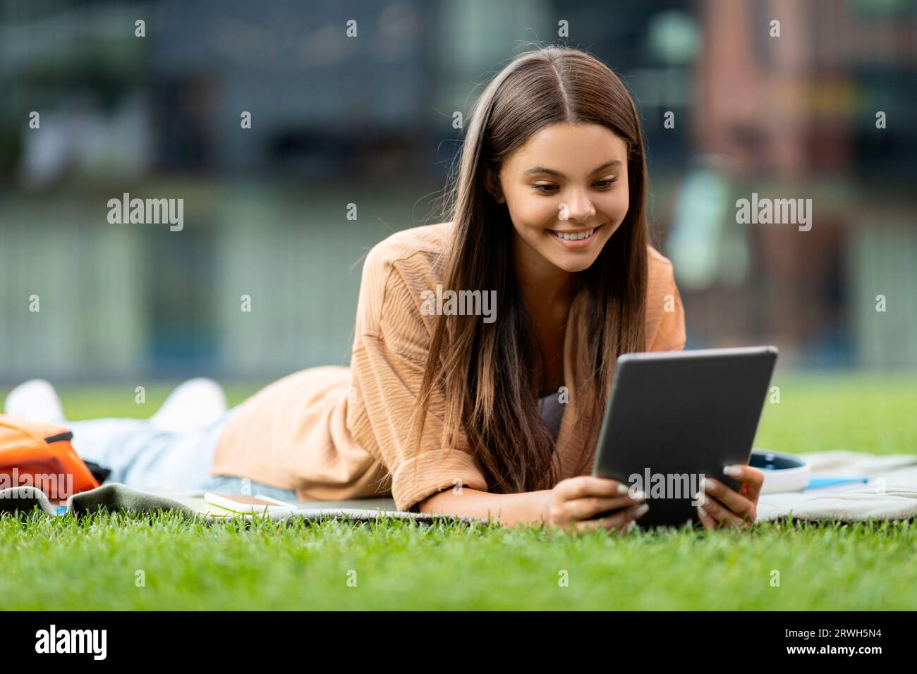 Relaxed young woman student lying on grass with digital tablet Stock Photo