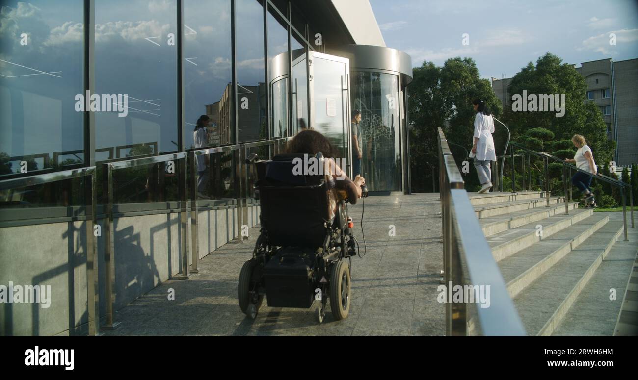 Woman with physical disability rides into clinic entrance on motorized