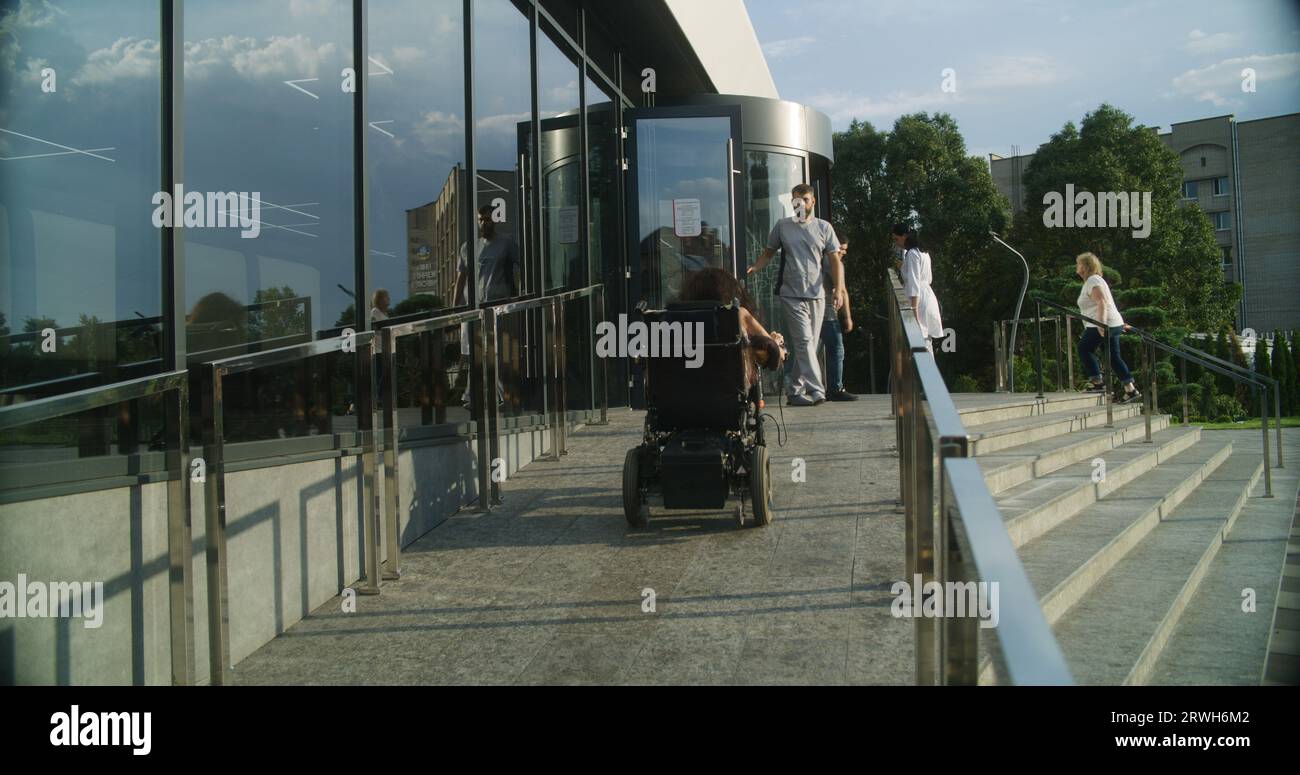 Woman with physical disability rides into clinic entrance on motorized