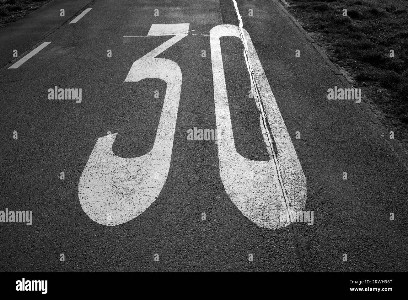 Painted number 30 for speed limit on a road in black and white Stock Photo