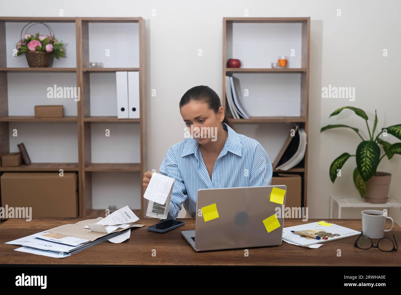 female accountant at home. calculating finances, using calculator. Managing freelance income taxes Stock Photo