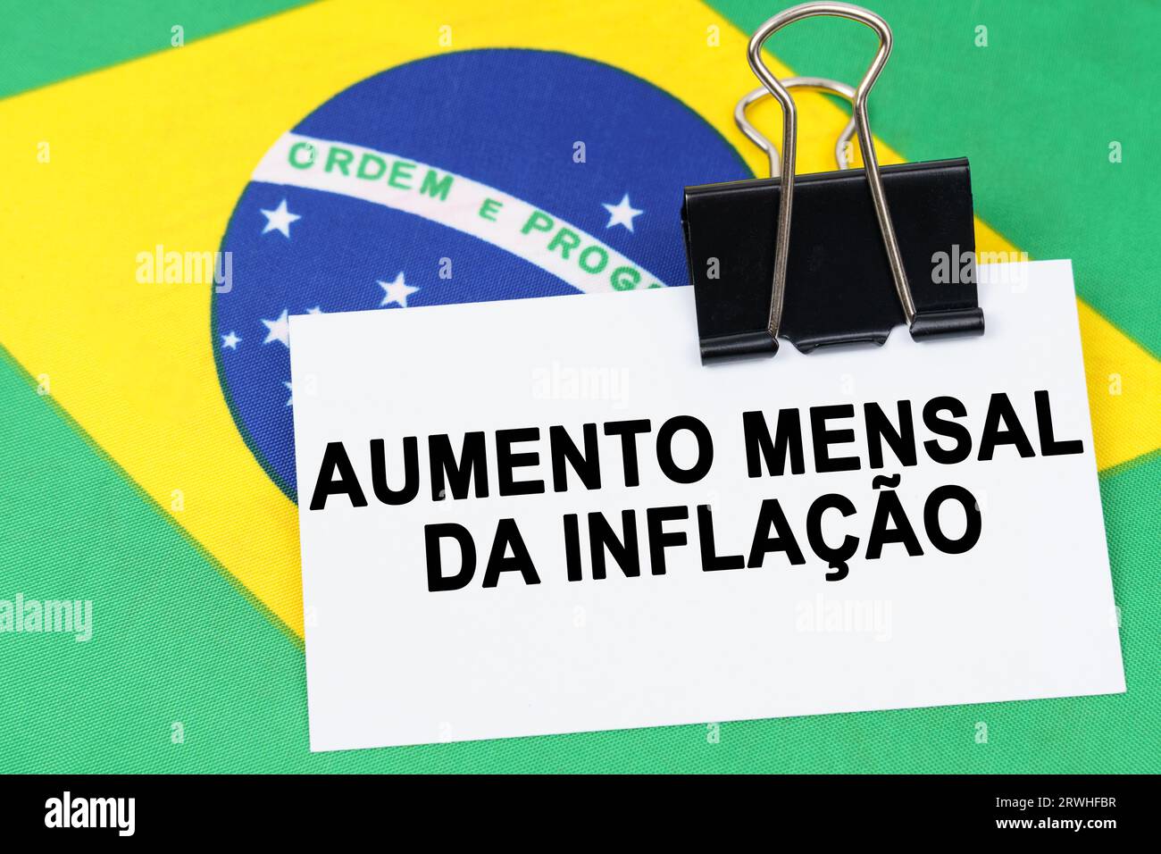 Economy and finance concept. On the flag of Brazil lies a business card with the inscription - monthly rise in inflation. Text in Portuguese. Stock Photo