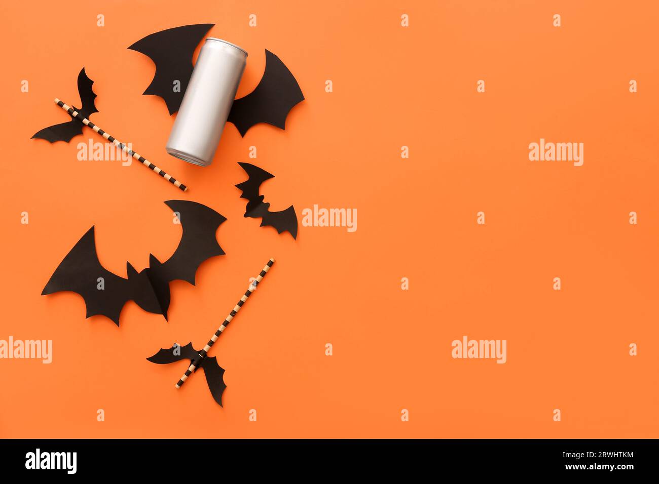 Straws with paper bats and can of beverage for Halloween on orange ...